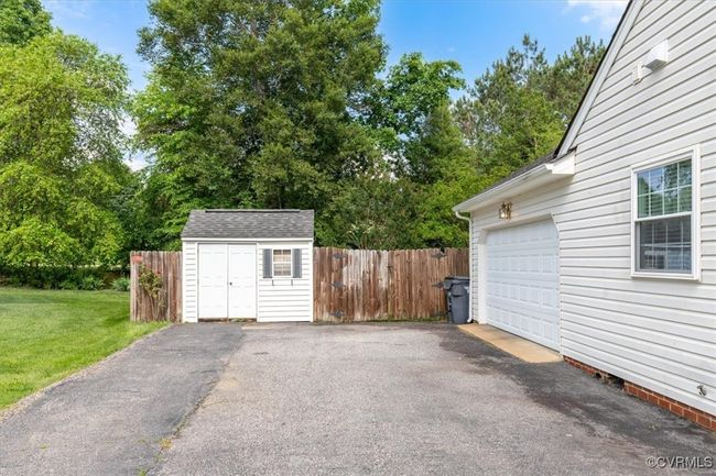 Garage featuring driveway, a storage unit, and view of wooded area | Image 39