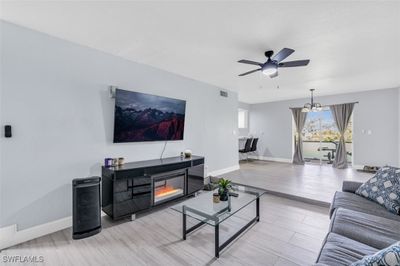 Living room featuring ceiling fan with notable chandelier and light hardwood / wood-style floors | Image 3