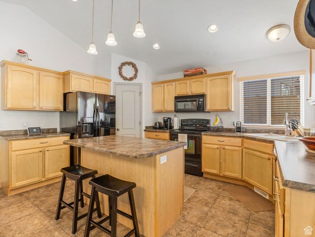 Kitchen with black appliances, light brown cabinets, a sink, and high vaulted ceiling | Image 12