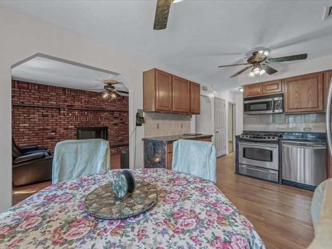 Dining room featuring ceiling fan, light wood finished floors, and a brick fireplace | Image 11