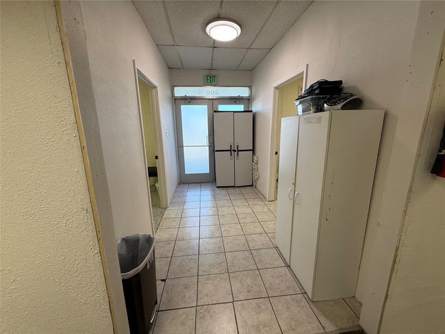 Hall featuring a drop ceiling, light tile patterned flooring, and a textured wall | Image 13