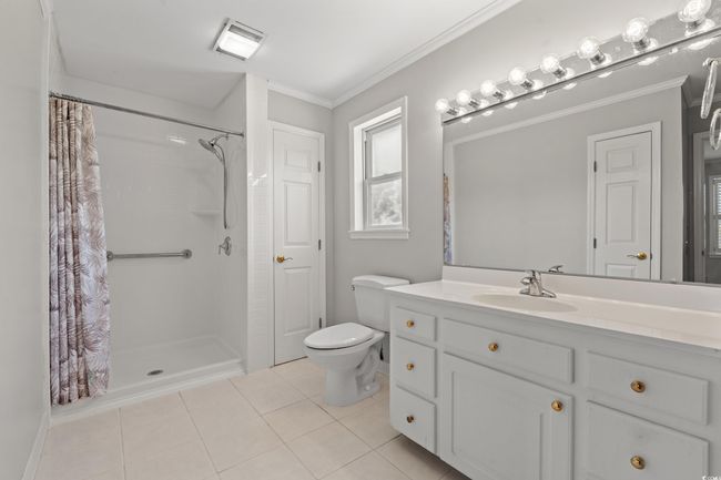 Full bathroom with tile patterned floors, a shower with shower curtain, vanity, and crown molding | Image 34