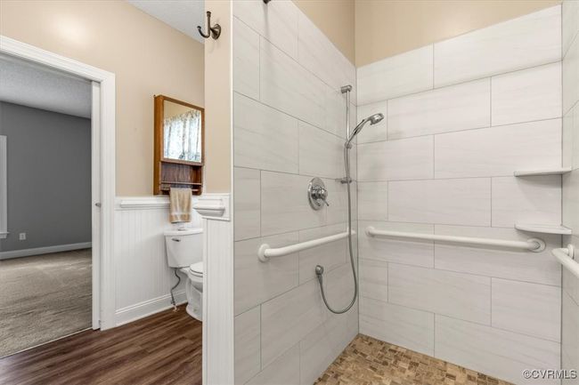 Full bathroom with tiled shower, wainscoting, toilet, and wood finished floors | Image 31