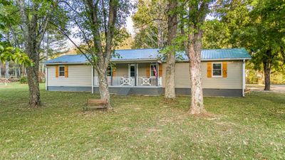 Metal roof, covered front porch, custom wood shutters, mature trees and a level lot... just to name a few. | Image 3