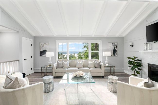 Living area with baseboard heating, wood finished floors, and a glass covered fireplace | Image 10