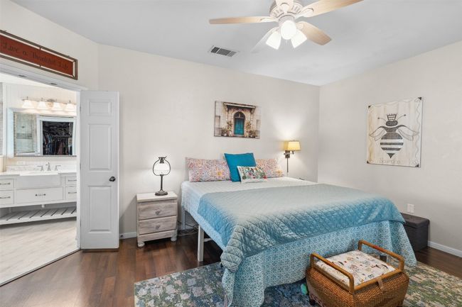 Bedroom with baseboards, visible vents, wood finished floors, ceiling fan, and ensuite bath | Image 8