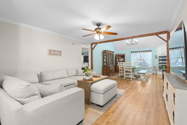 Living room with a chandelier, ceiling fan, light wood-style flooring, and crown molding | Image 6