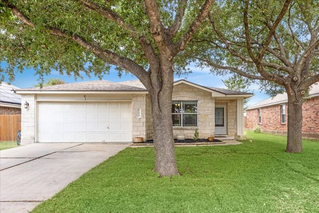 View of front of home featuring large trees, 2-car garage, front yard, and limestone siding | Image 28