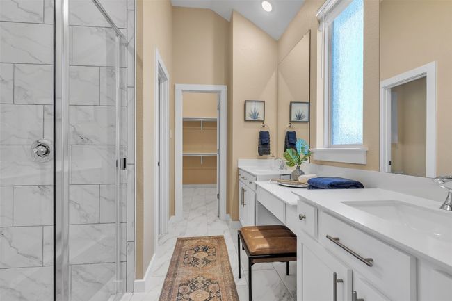 Full bath featuring marble look tiles, double vanity, a shower stall, a walk in closet, and lofted ceiling | Image 19