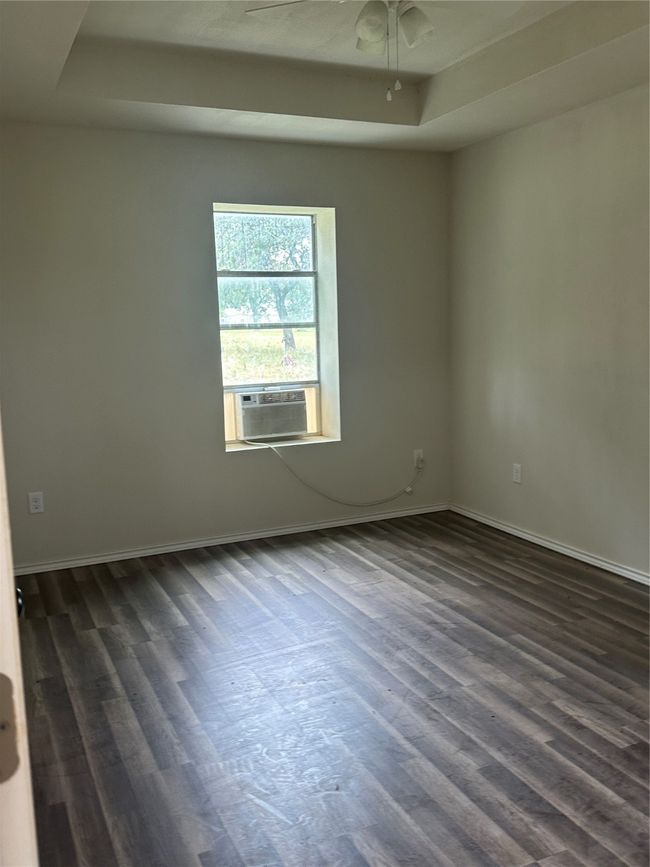 Spare room with dark wood-style flooring, a ceiling fan, baseboards, and a raised ceiling | Image 18