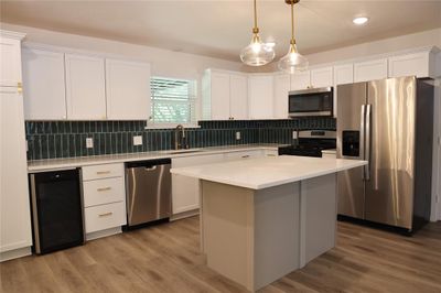 Kitchen featuring appliances with stainless steel finishes, a kitchen island, wine cooler, and white cabinetry | Image 3