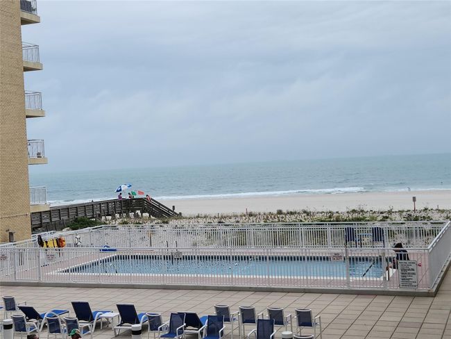 Community pool featuring view of water and beach and a patio | Image 13