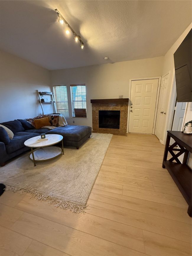 Living room featuring light wood-type flooring, a textured ceiling, and a premium fireplace | Image 8