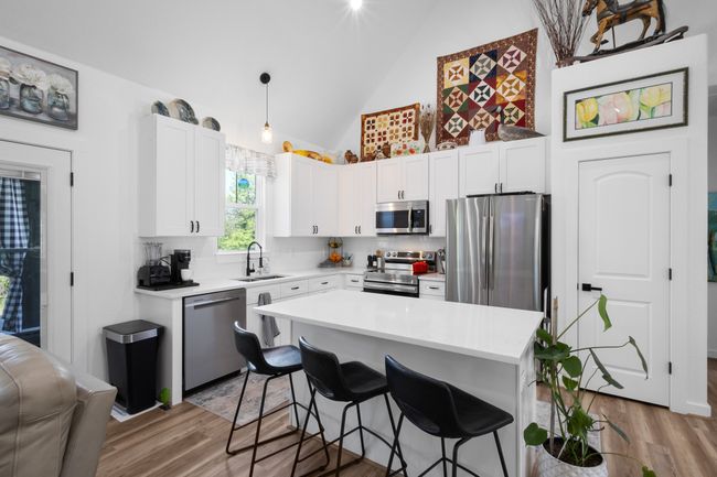 Kitchen with a sink, light countertops, appliances with stainless steel finishes, light wood finished floors, and a breakfast bar area | Image 12