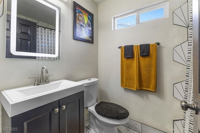 Bathroom with toilet, marble finish floor, vanity, and a textured wall | Image 23