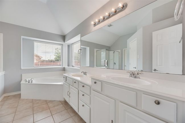 Full bath featuring lofted ceiling, double vanity, a shower stall, a bath, and tile patterned floors | Image 17
