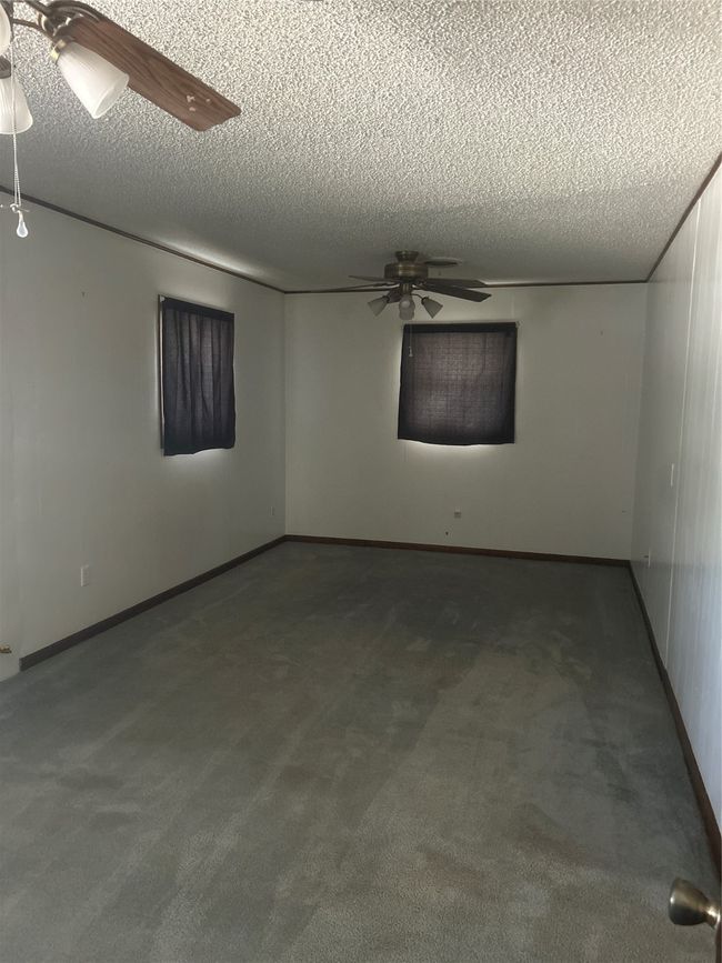 Spare room featuring a ceiling fan, a textured ceiling, carpet floors, and baseboards | Image 10