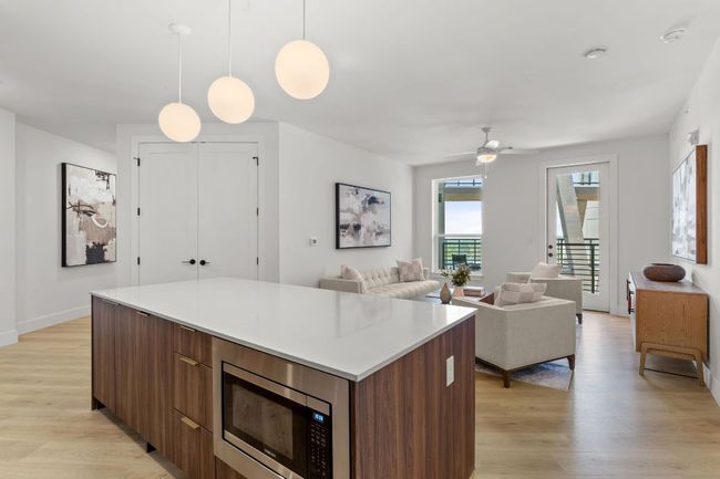 Kitchen with stainless steel microwave, a kitchen island, light wood-style floors, and modern cabinets | Image 4