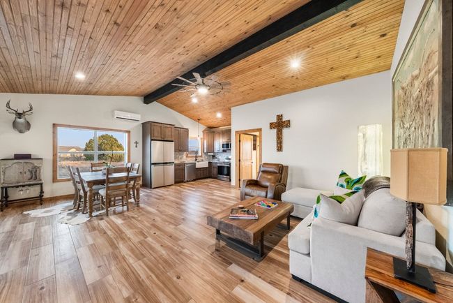 Living area with lofted ceiling with beams, light wood-style flooring, wood ceiling, a ceiling fan, and a wall mounted AC | Image 14