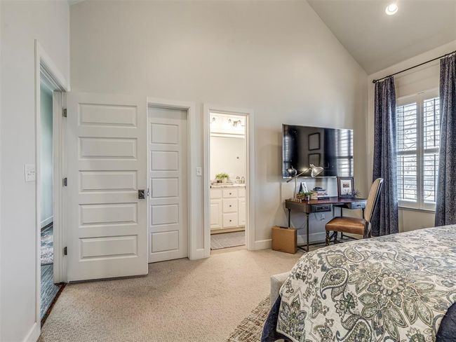Carpeted bedroom with high vaulted ceiling, connected bathroom, and baseboards | Image 15