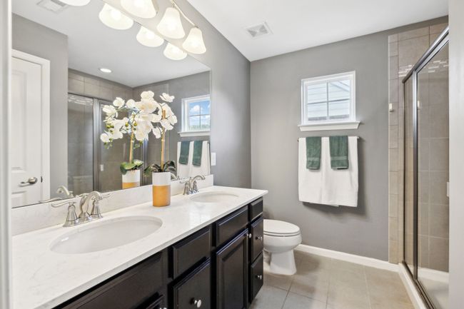 The primary bath features a tile floor, tall double vanity with drawer stacks and cabinets as well as an oversized shower. An elevated window allows the light but keeps the privacy | Image 22