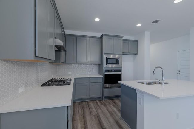 Kitchen featuring a sink, stainless steel appliances, visible vents, backsplash, and dark wood-style floors | Image 13