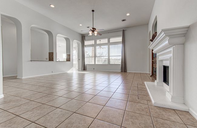 Unfurnished living room featuring baseboards, light tile patterned flooring, a fireplace with raised hearth, recessed lighting, and ceiling fan | Image 9