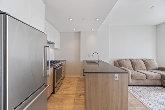 Kitchen with a sink, appliances with stainless steel finishes, dark countertops, open floor plan, and recessed lighting | Image 6