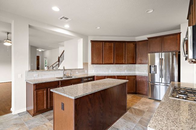 Kitchen with stainless steel appliances, visible vents, a sink, a kitchen island, and tasteful backsplash | Image 11