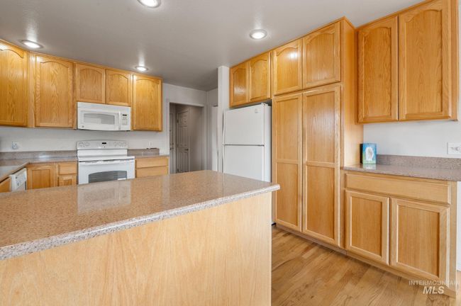 Kitchen featuring white appliances, light wood-type flooring, recessed lighting, and light stone counters | Image 11