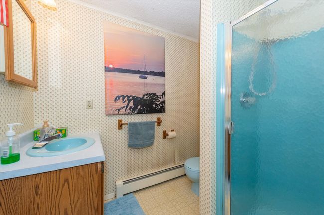 Bathroom with a baseboard radiator, a shower stall, and wallpapered walls | Image 15