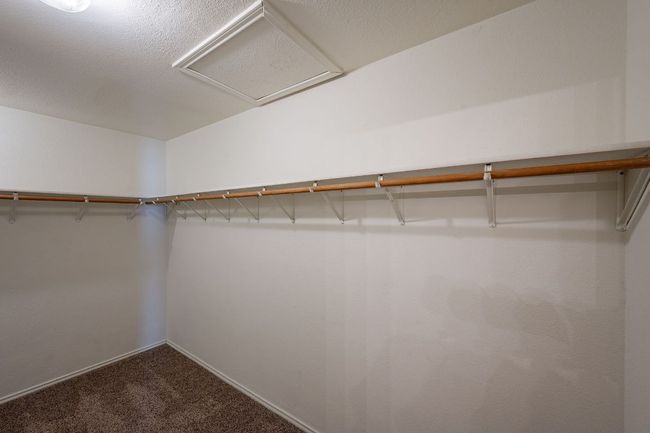 Walk in closet with dark colored carpet and attic access | Image 20