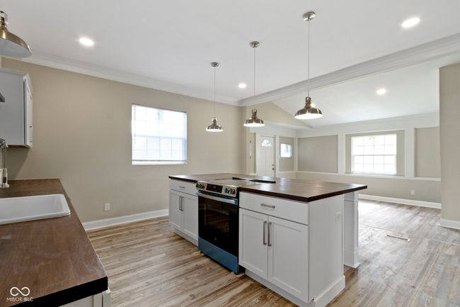 kitchen featuring butcher block countertops, electric range, baseboards, light wood-type flooring, and ornamental molding | Image 14