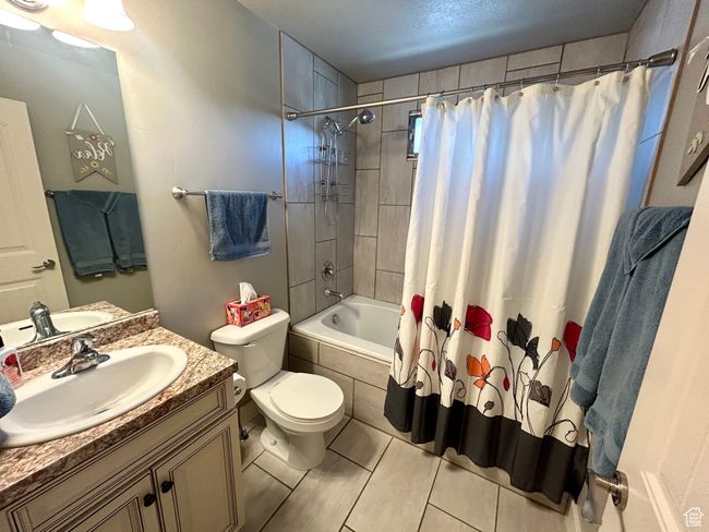 Full bathroom with toilet, tiled shower / bath combo, vanity, and tile patterned floors | Image 21