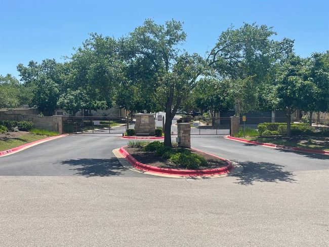 View of asphalt street featuring a gate, curbs, and a gated entry | Image 18