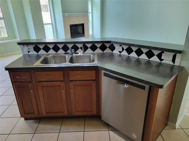 Kitchen featuring stainless steel dishwasher, dark countertops, healthy amount of natural light, and light tile patterned floors | Image 7