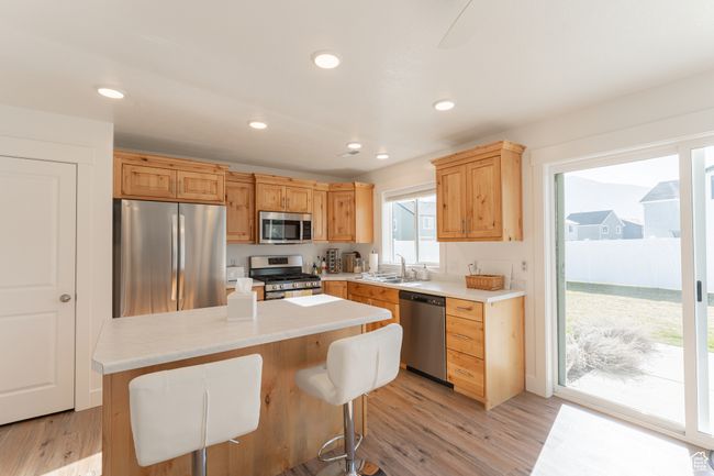Kitchen featuring light wood-style flooring, light countertops, a sink, and appliances with stainless steel finishes | Image 6