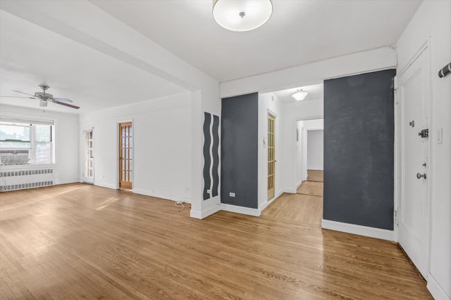Unfurnished room with radiator heating unit, light wood finished floors, and a ceiling fan | Image 4