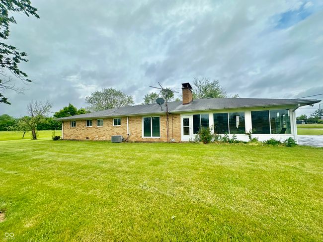 rear view of property featuring a chimney, central air condition unit, a yard, and brick siding | Image 10