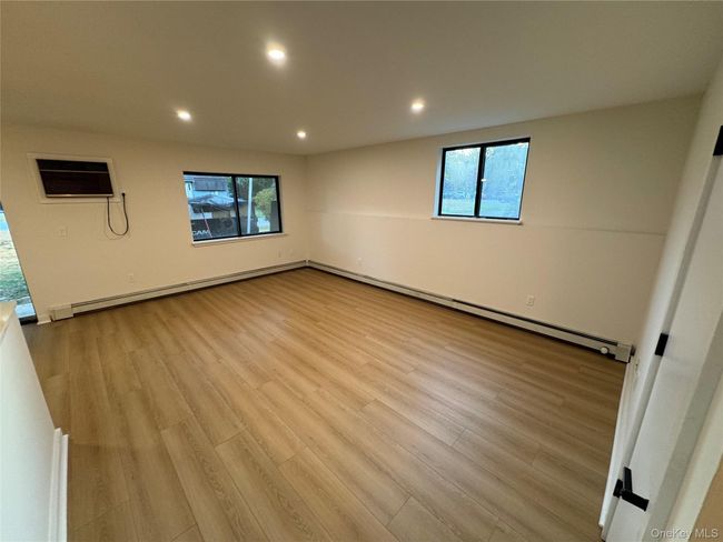 Spare room with healthy amount of natural light, baseboard heating, wood finished floors, and recessed lighting | Image 14