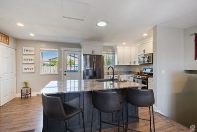 Kitchen with sink, dark hardwood / wood-style flooring, a kitchen breakfast bar, stainless steel appliances, and white cabinets | Image 3