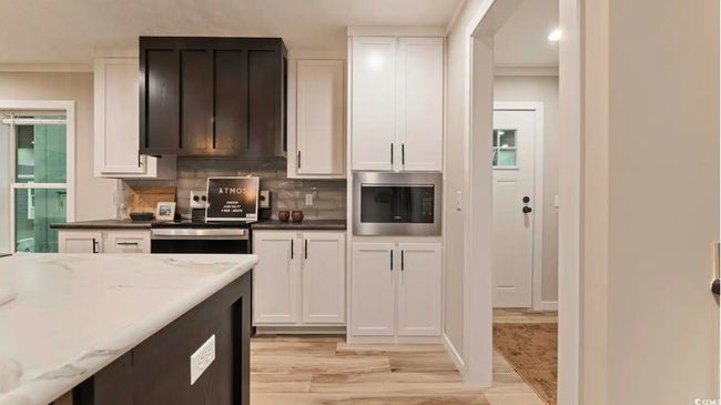 Kitchen with stainless steel microwave, light wood-style floors, white cabinetry, ornamental molding, and recessed lighting | Image 10