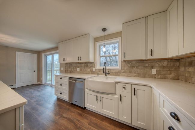 Kitchen featuring backsplash, stainless steel dishwasher, a sink, dark wood-style flooring, and white cabinetry | Image 11