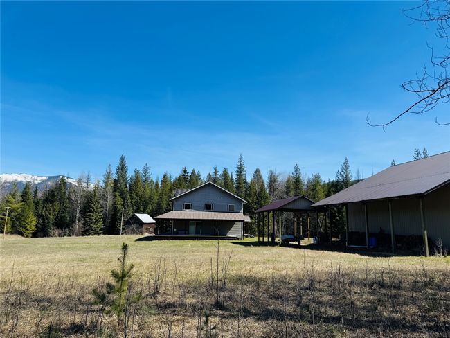 View of yard with a detached carport, a view of trees, an outbuilding, and an outdoor structure | Image 6