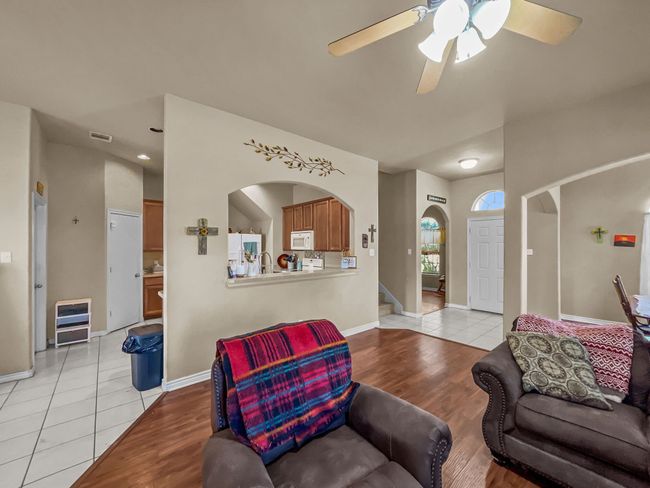 Living room featuring light wood-type flooring, a ceiling fan, arched walkways, stairs, and baseboards | Image 4