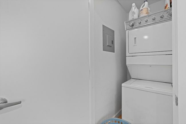 Laundry area featuring stacked washer and clothes dryer and electric panel | Image 21