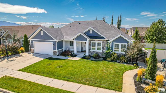 View of front of house featuring concrete driveway, fence, an attached garage, stone siding, and a front lawn | Image 44