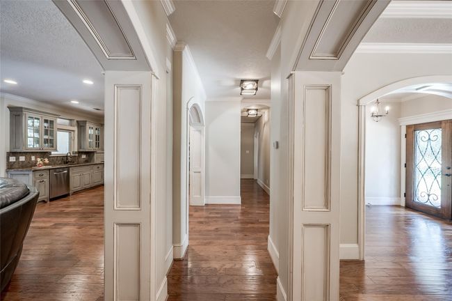 Explore the elegant hallway with charming arches leading to two spacious downstairs bedrooms and a convenient Jack and Jill bath. | Image 16