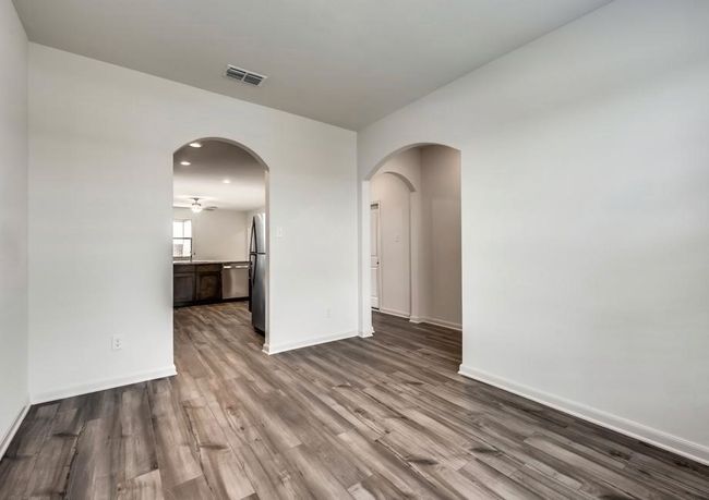 Spare room with dark wood-style floors, visible vents, arched walkways, and baseboards | Image 4