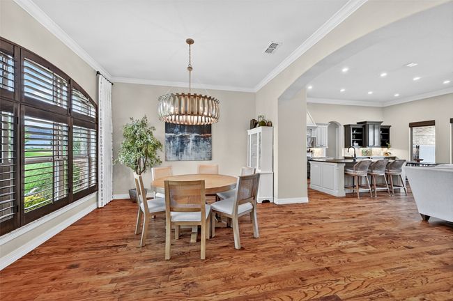 Dining area with arched walkways, healthy amount of natural light, light wood-style floors, a chandelier, and crown molding | Image 5